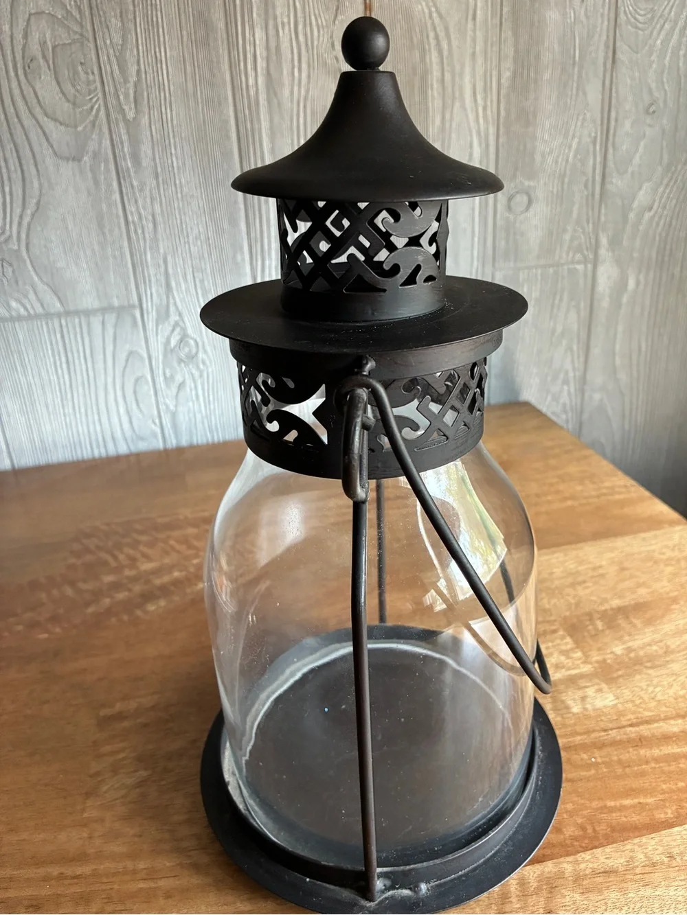 Decorative black metal hurricane lantern/candle lantern. It has a clear glass